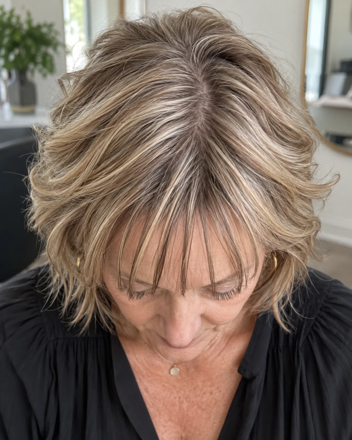 Top-down view of mature woman's crown showing a piece-y fringe with deliberate separation between razor-cut sections, gaps styled as design rather than thinning