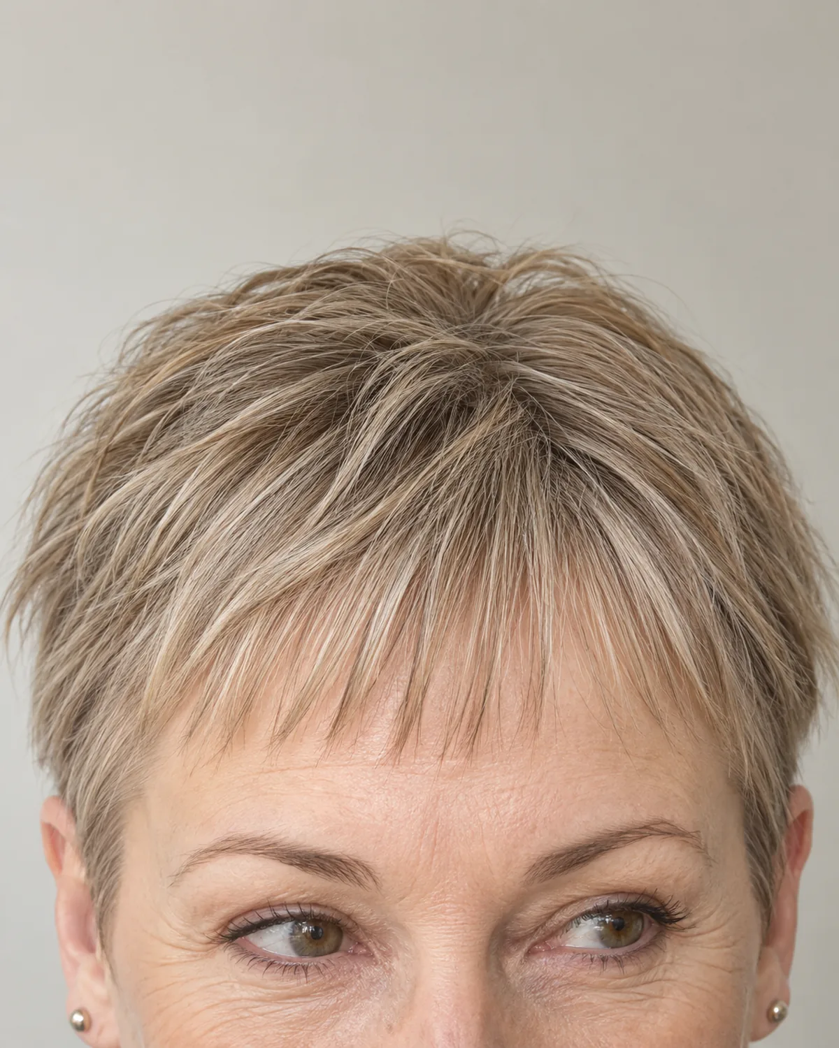 Close crop of forehead and hairline showing very short tapered baby bangs, fuller at the centre and thinner at the temples, fine strands visible