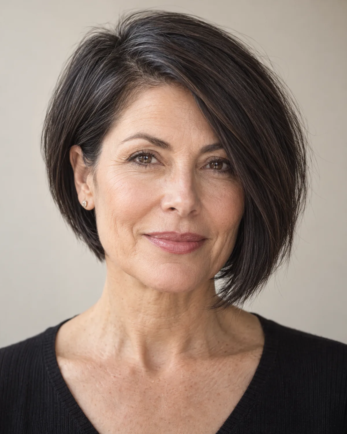 Front view of woman over 50 with dark chin-length A-line bob, shorter in back and gradually longer toward the chin, diagonal line visible