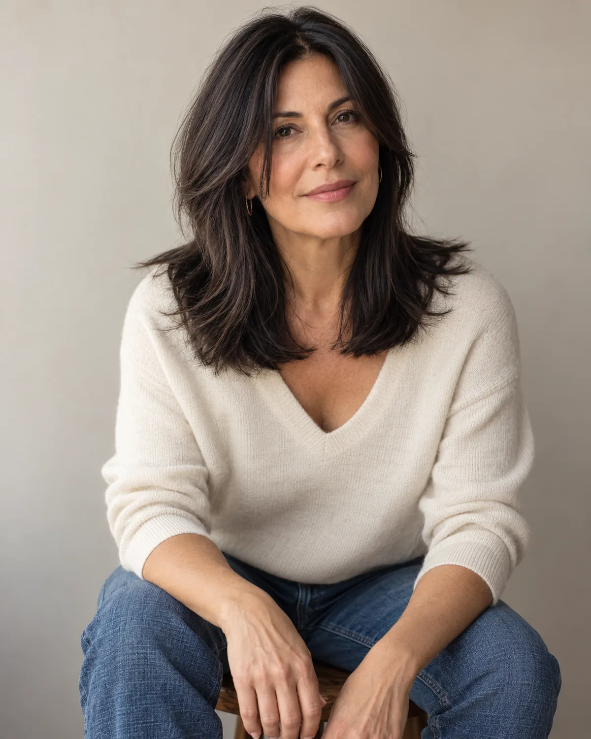 Seated woman over 50 with dark mid-length hair and two shorter disconnected front pieces, pieces casting visible shadows on the face