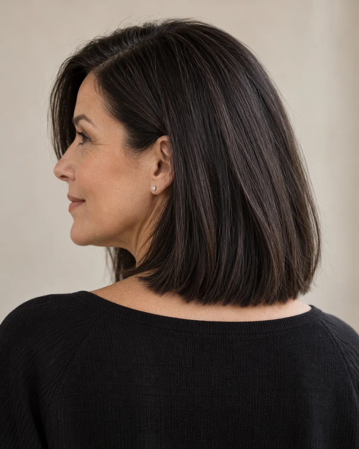 Rear view of woman over 50 with dark side-parted lob at collarbone length, single blunt hemline visible from behind
