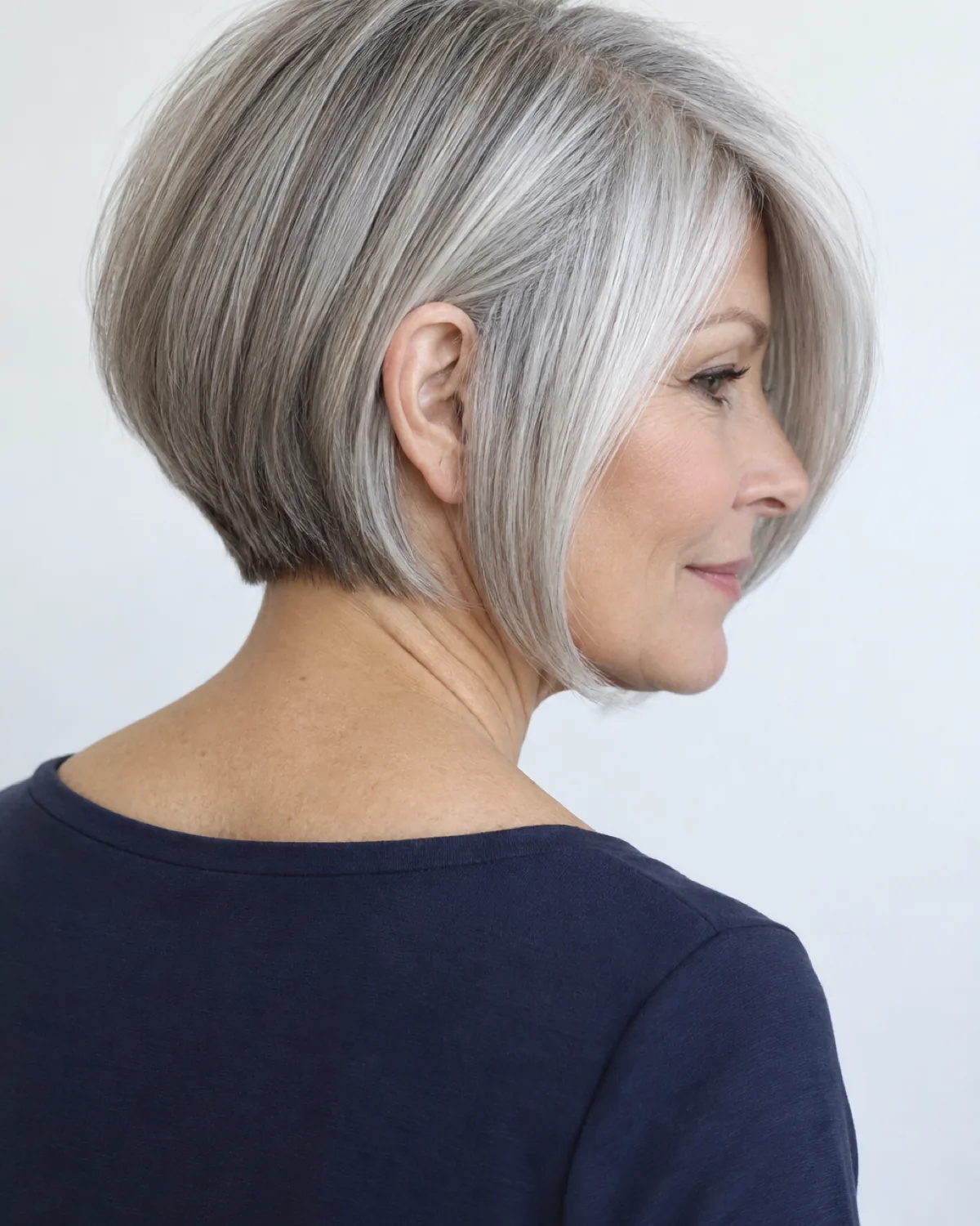 Woman over 50 in back-three-quarter view with silver-grey graduated bob and side-parted bangs