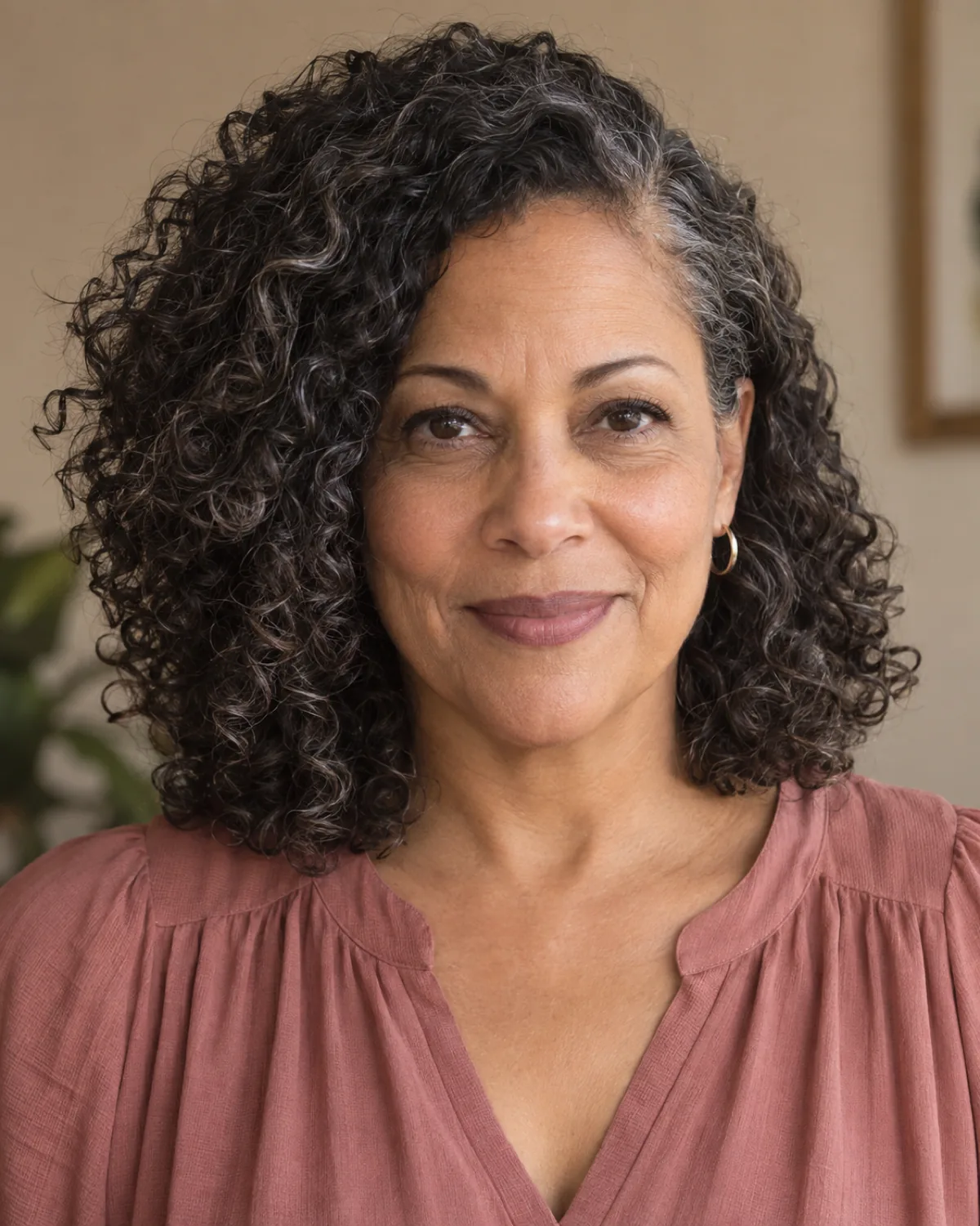 Front-facing mature woman with shoulder-length natural curls and deep side part creating asymmetric volume