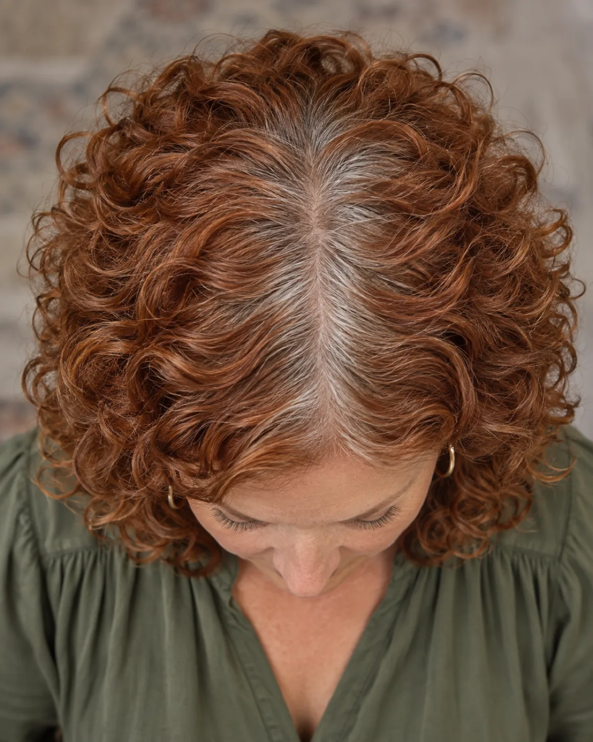 Top-down macro of part line and crown showing curls radiating outward in a contained rounded silhouette