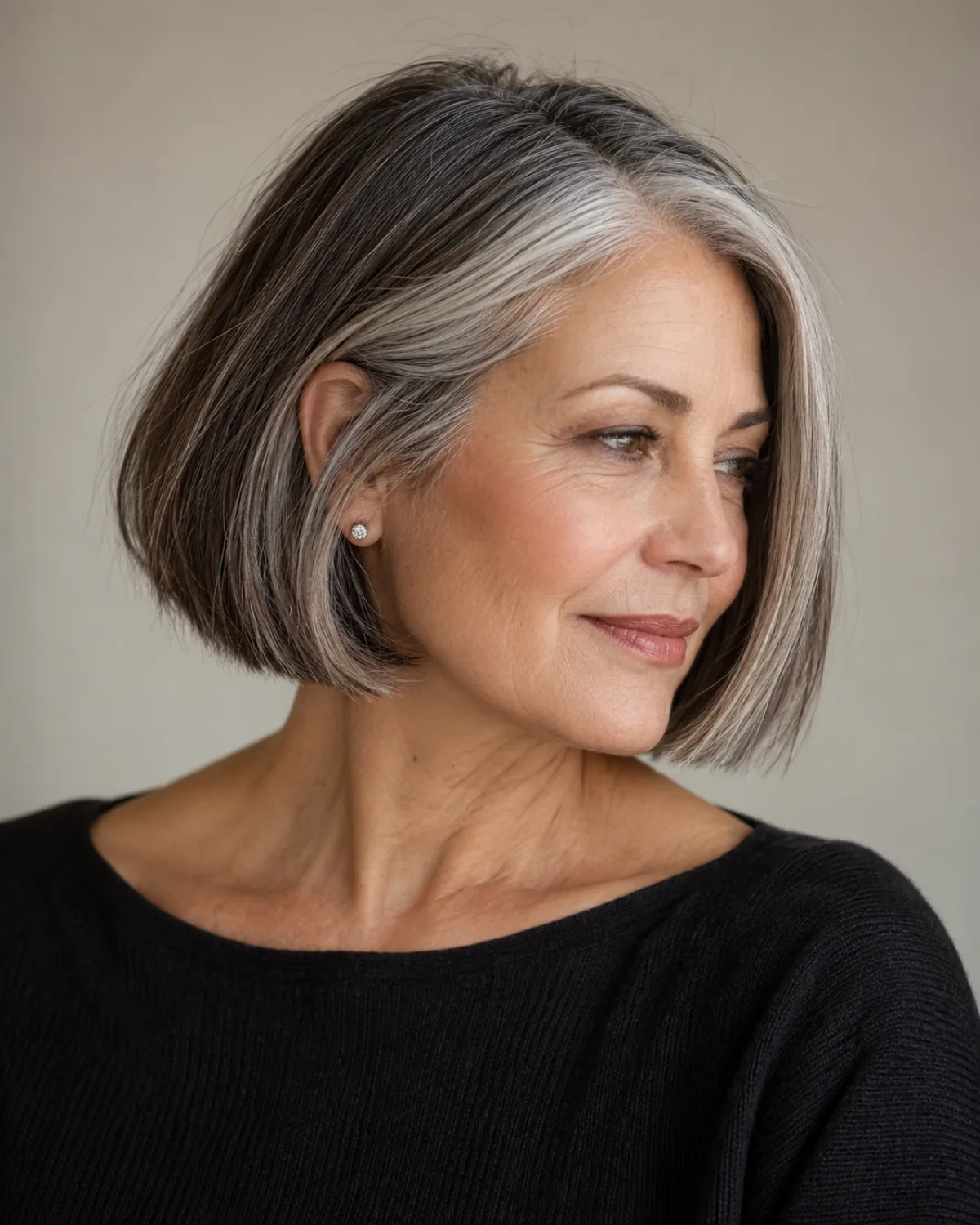 Three-quarter right profile of mature woman with chin-length blunt bob, gray concentrating at the temples and framing the face