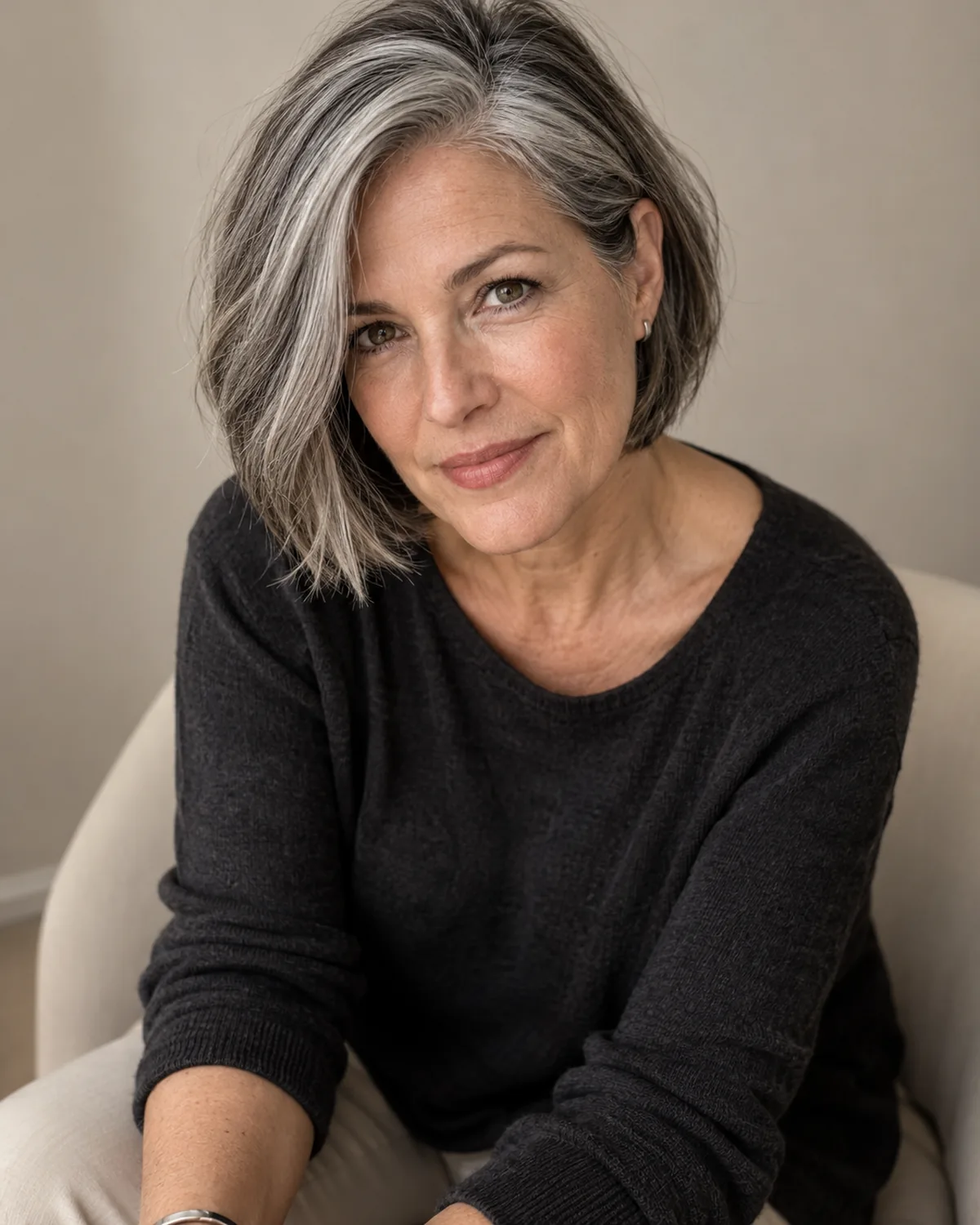 Three-quarter seated view of mature woman with side-parted chin-length bob, grayer temple sweeping forward across the face