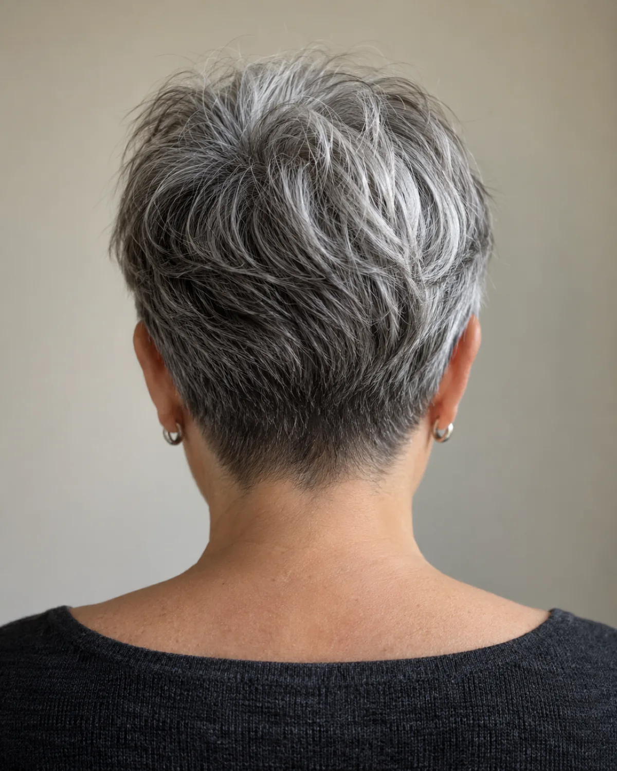 Behind view of mature woman with tapered nape pixie, tight nape and silver-white blend visible at the crown