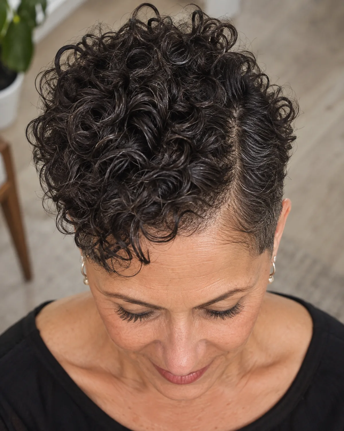 Top-down macro view of mature woman with dark tight curls on top contrasting with quarter-inch cropped sides, curl definition visible