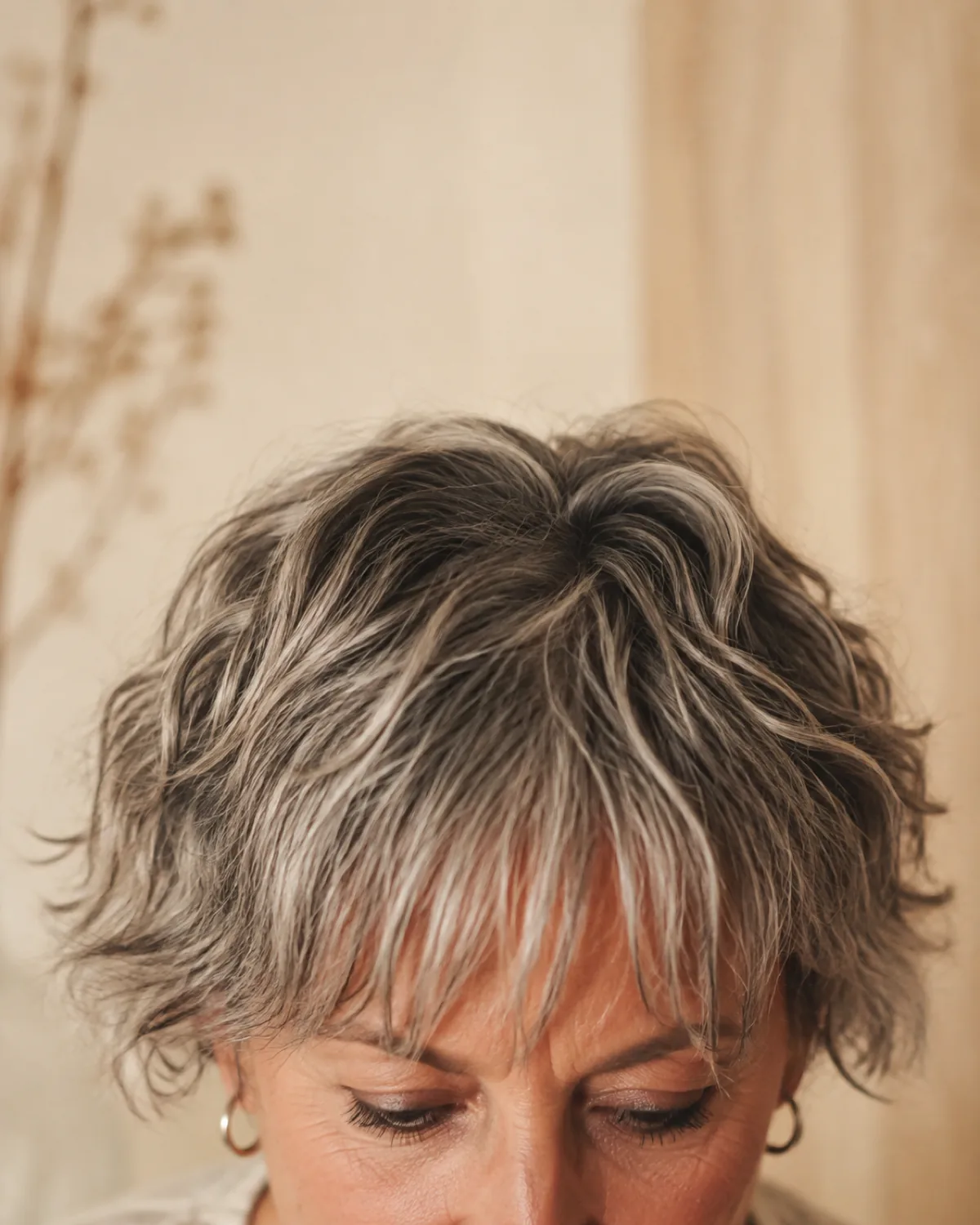 Close-up of textured crop fringe on a mature woman showing choppy point-cut pieces in wavy grey hair