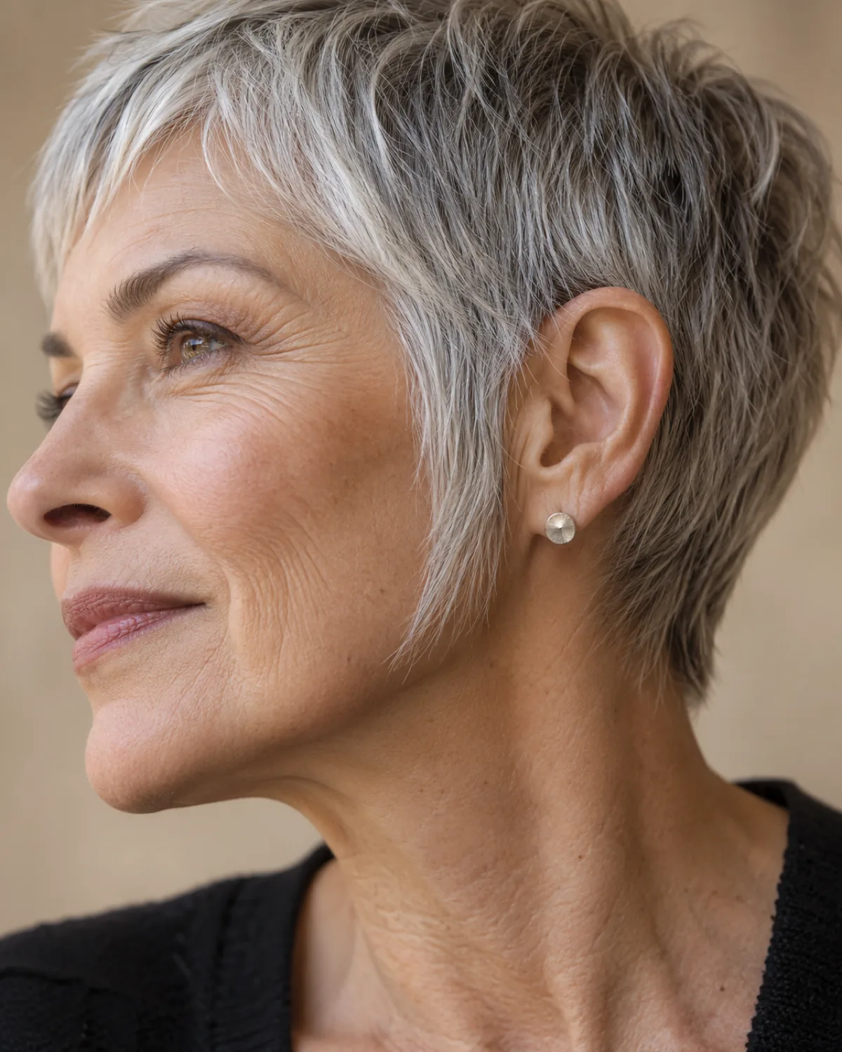 Close-up of the ear and jawline area of mature woman over 60 with pixie and extended sideburns, tapered silver sideburn piece framing the jaw